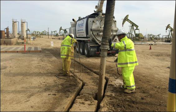 Two-person hydro excavation crew daylighting buried utilities in protective gear